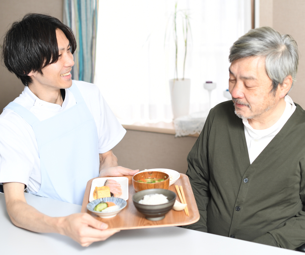 A photograph of a careworker presenting a meal to a gentleman