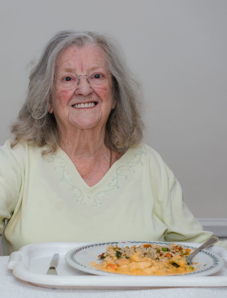 A photograph of a lady with a plate of curry and rice