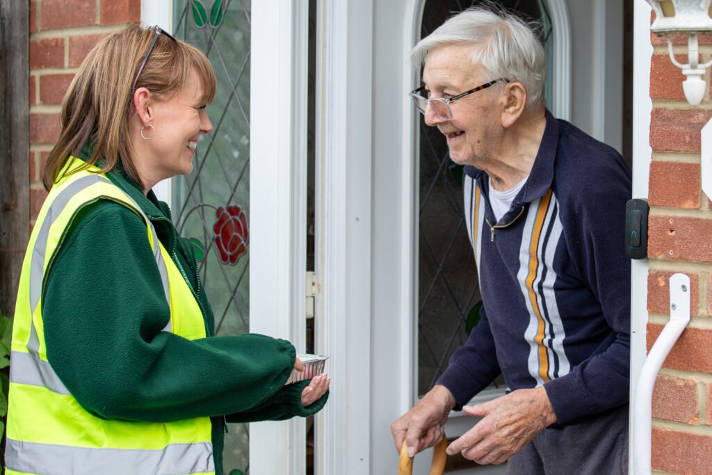 A Meals on Wheels driver delivers a meal to a client