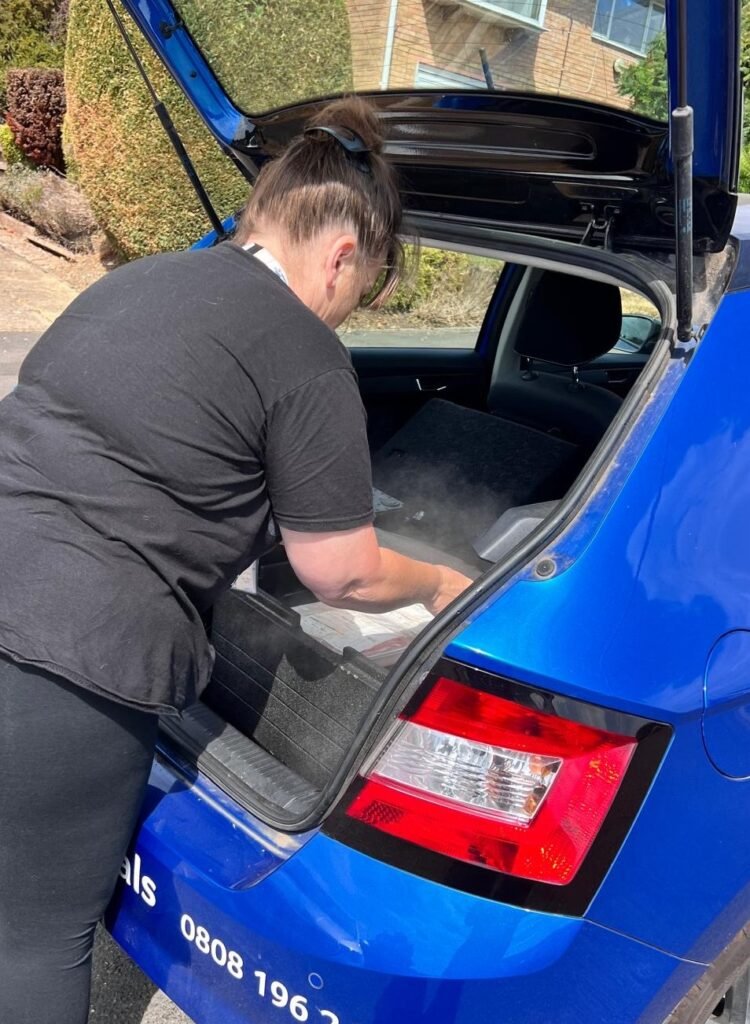 A woman loading a car with meals, ready for the delivery round